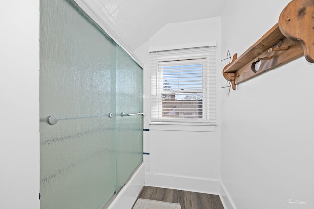 bathroom featuring lofted ceiling, wood-type flooring, and bath / shower combo with glass door