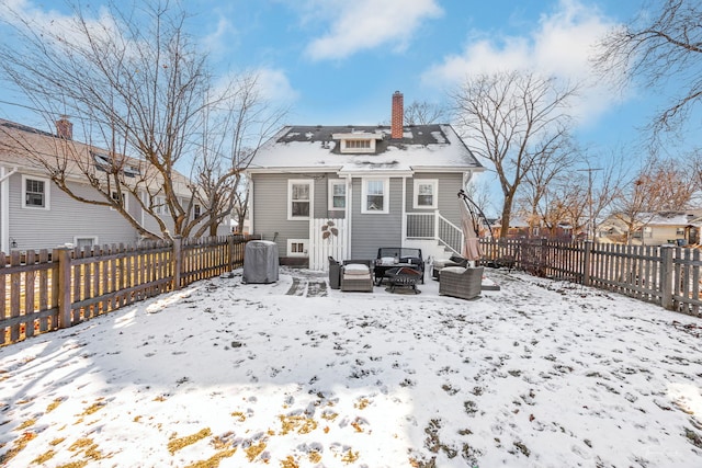 snow covered rear of property featuring a fire pit