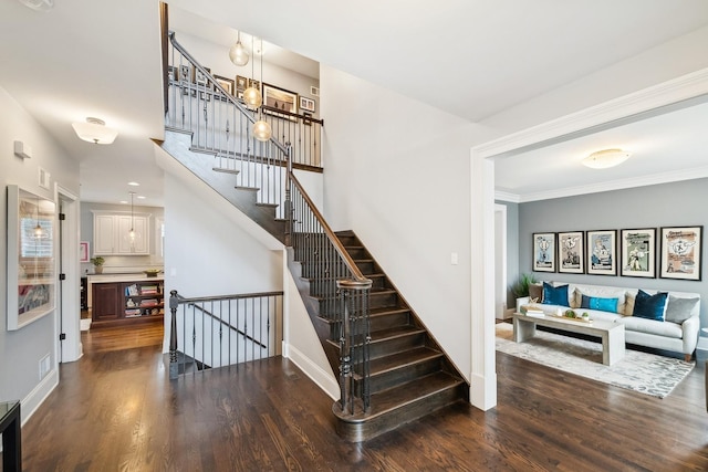 staircase featuring ornamental molding, wood finished floors, visible vents, and baseboards