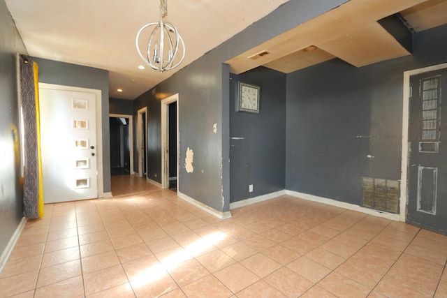 empty room with light tile patterned flooring and a chandelier