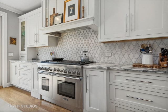 kitchen featuring white cabinetry, double oven range, backsplash, and light stone countertops