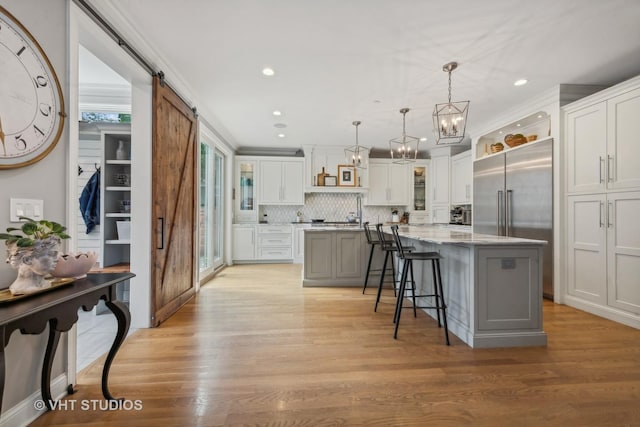 kitchen with a breakfast bar area, light wood-type flooring, a kitchen island, pendant lighting, and a barn door