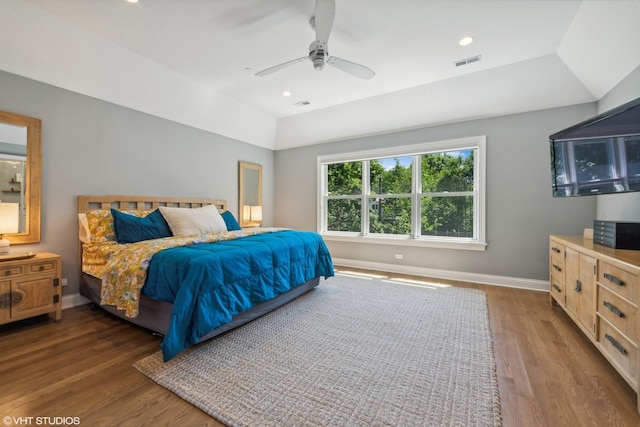 bedroom featuring lofted ceiling, dark wood-type flooring, ceiling fan, and a tray ceiling