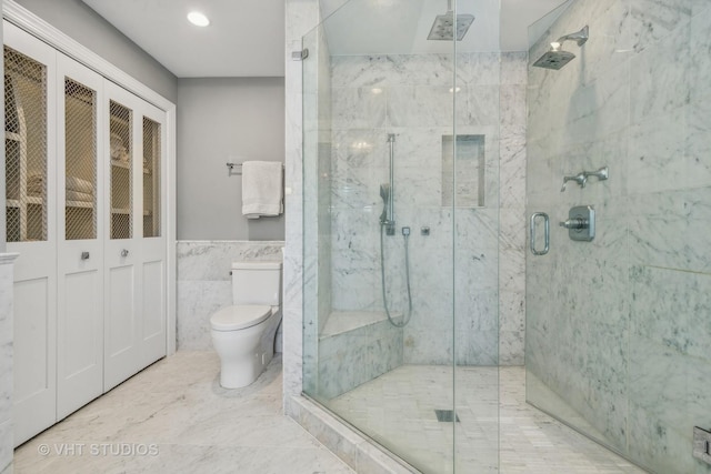 bathroom with toilet, a shower with shower door, and tile walls