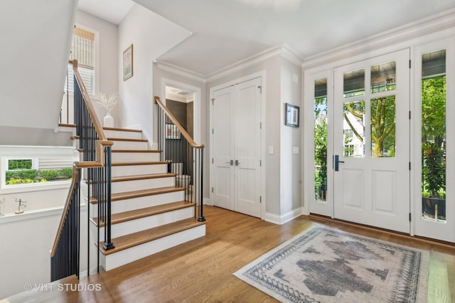 entryway with ornamental molding and light wood-type flooring