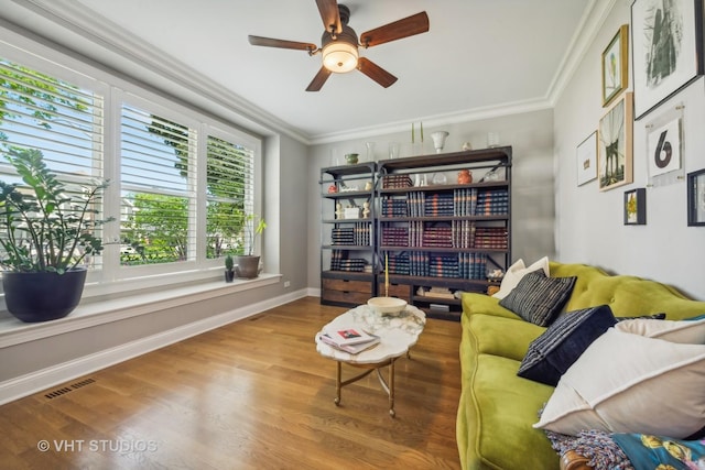 living area featuring hardwood / wood-style flooring, crown molding, and ceiling fan