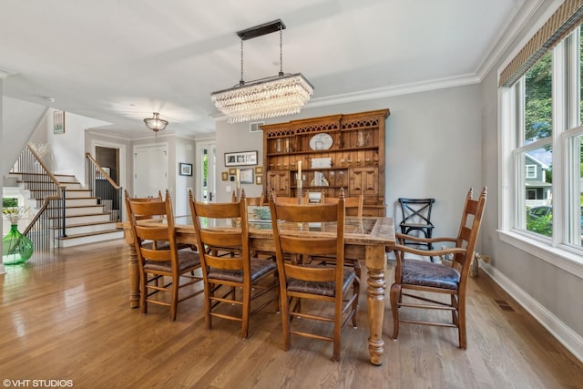 dining space featuring a notable chandelier, ornamental molding, and light hardwood / wood-style floors