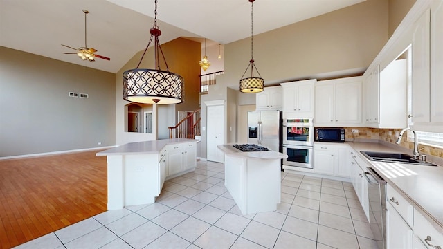 kitchen featuring appliances with stainless steel finishes, a center island, sink, and light tile patterned floors