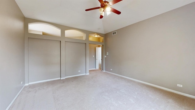 unfurnished bedroom with light carpet, multiple closets, vaulted ceiling, and ceiling fan