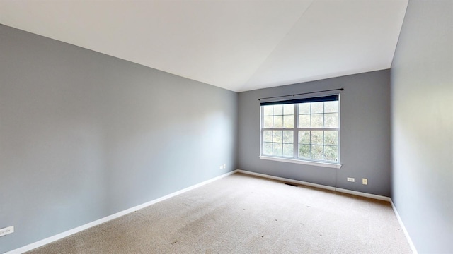 carpeted spare room with lofted ceiling