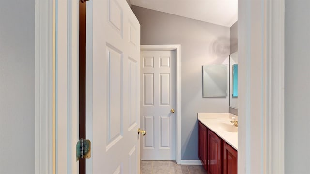 bathroom with tile patterned floors, vanity, and vaulted ceiling