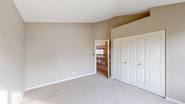 unfurnished bedroom with a closet, lofted ceiling, and light carpet