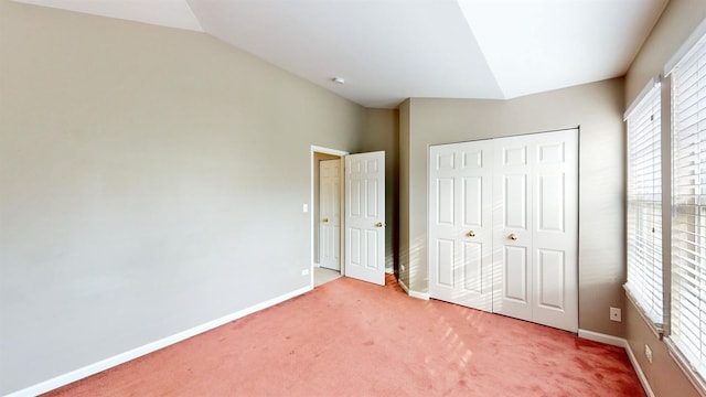 unfurnished bedroom featuring vaulted ceiling, a closet, and carpet flooring