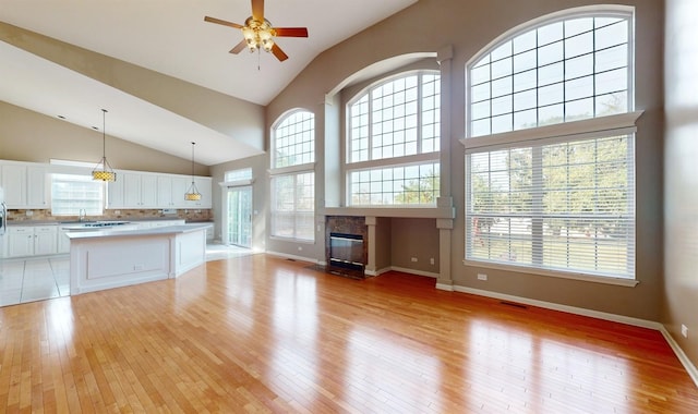 unfurnished living room with ceiling fan, sink, a high end fireplace, and light wood-type flooring