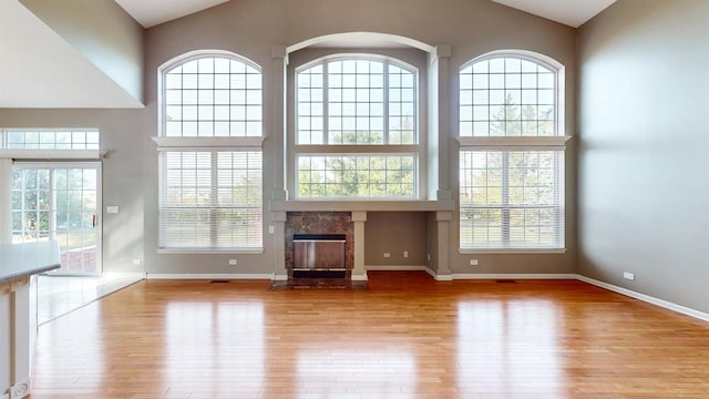 unfurnished living room with a high end fireplace, light hardwood / wood-style flooring, and a high ceiling