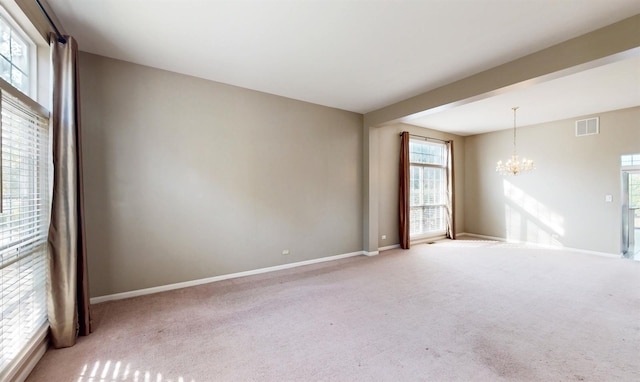 carpeted empty room featuring a chandelier