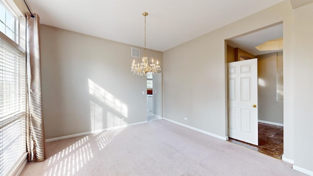 empty room with a wealth of natural light, carpet floors, and a chandelier