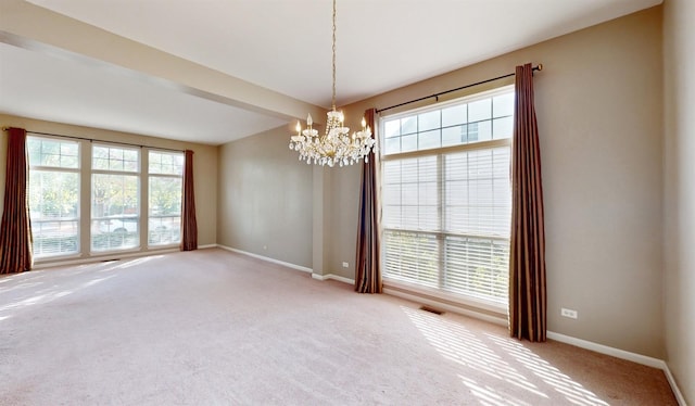 carpeted spare room featuring a chandelier