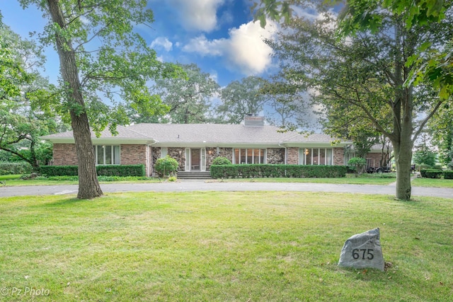 single story home with driveway, a front lawn, and brick siding