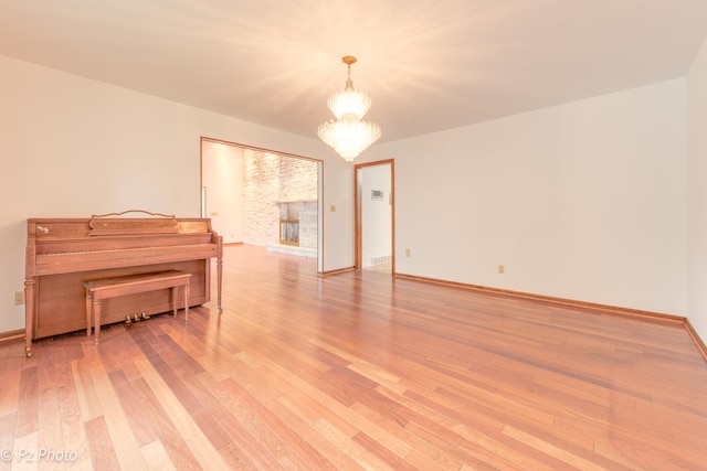 unfurnished room featuring light wood-style flooring, baseboards, and a notable chandelier