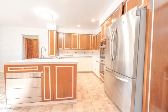 kitchen featuring recessed lighting, a sink, light countertops, freestanding refrigerator, and decorative backsplash