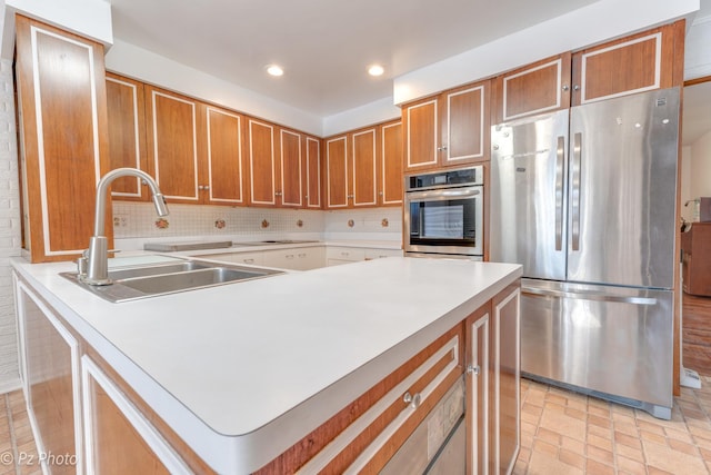 kitchen featuring recessed lighting, light countertops, backsplash, appliances with stainless steel finishes, and a sink