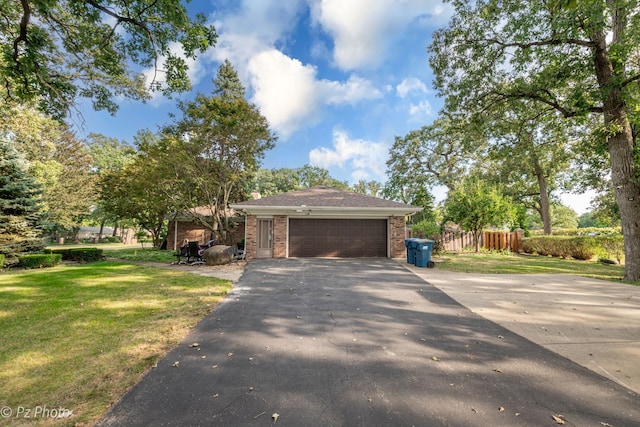 view of front of house with an attached garage, brick siding, fence, driveway, and a front lawn