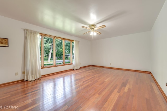 empty room featuring ceiling fan, light wood-type flooring, and baseboards