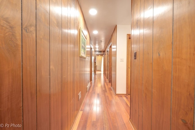 hallway with light wood-style floors and wooden walls