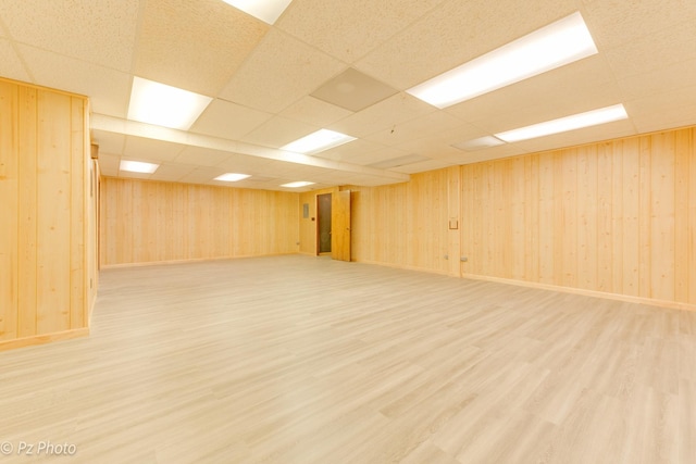 finished below grade area featuring light wood-type flooring, baseboards, and a paneled ceiling