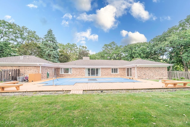 rear view of house featuring a chimney, fence, a deck, a yard, and brick siding