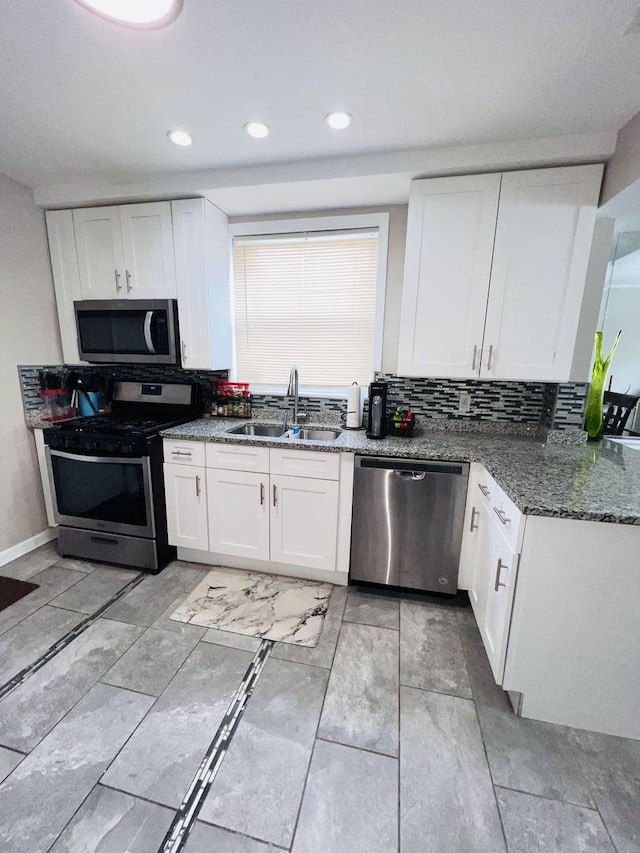 kitchen featuring white cabinetry, sink, dark stone counters, and appliances with stainless steel finishes