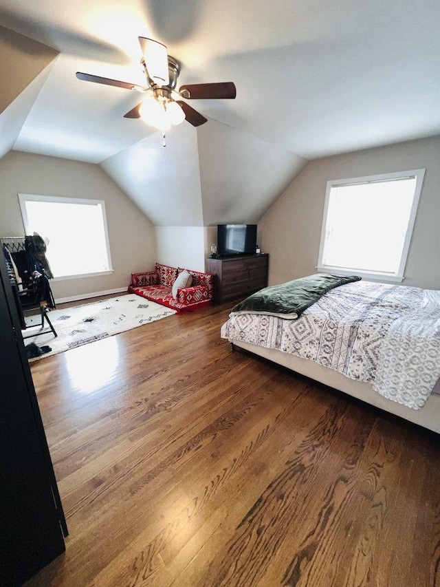 bedroom featuring multiple windows, hardwood / wood-style flooring, lofted ceiling, and ceiling fan