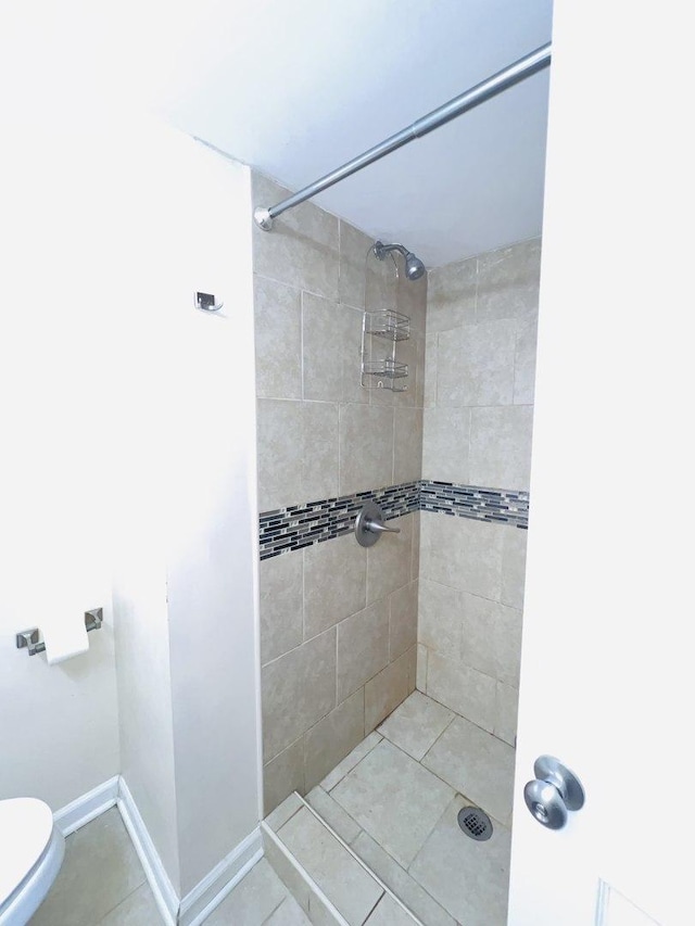 bathroom with tile patterned floors, toilet, and tiled shower