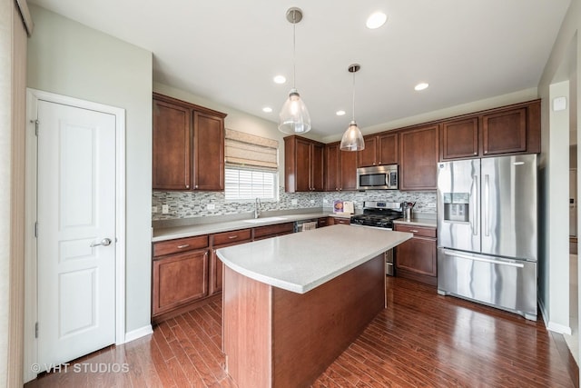 kitchen with a kitchen island, decorative light fixtures, sink, dark hardwood / wood-style flooring, and stainless steel appliances