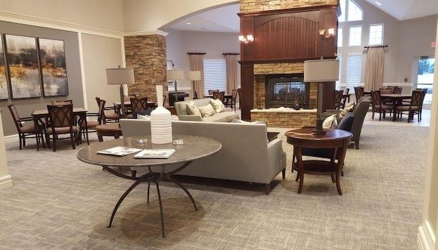 carpeted living room featuring a stone fireplace and high vaulted ceiling