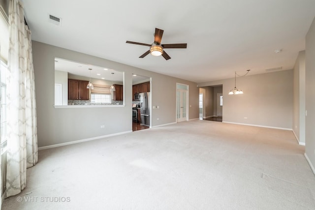 unfurnished living room with ceiling fan with notable chandelier and dark colored carpet