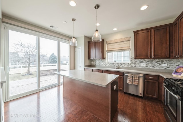 kitchen featuring pendant lighting, sink, stainless steel appliances, dark hardwood / wood-style floors, and a center island