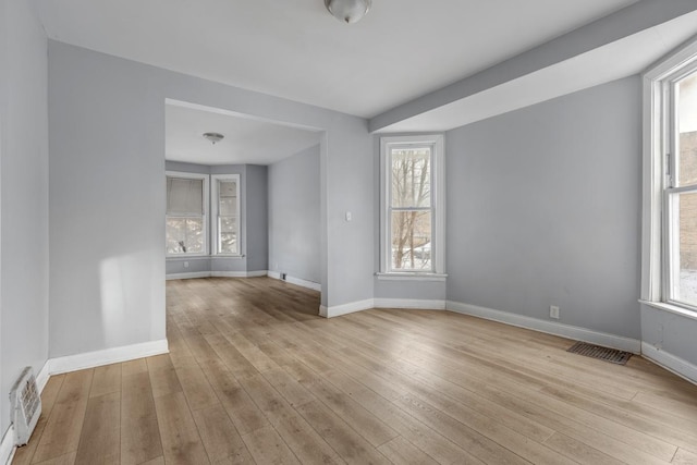 empty room with light hardwood / wood-style flooring and a wealth of natural light