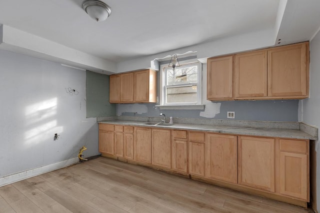 kitchen with light brown cabinetry, sink, and light hardwood / wood-style flooring