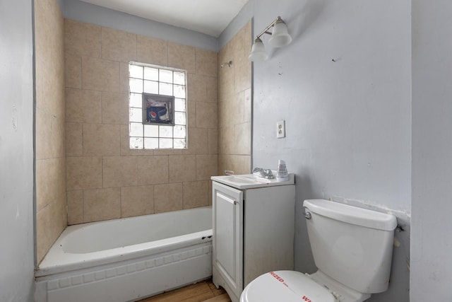 full bathroom featuring tiled shower / bath, vanity, and toilet