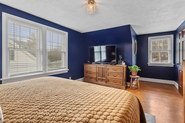 bedroom with multiple windows, wood-type flooring, and a textured ceiling