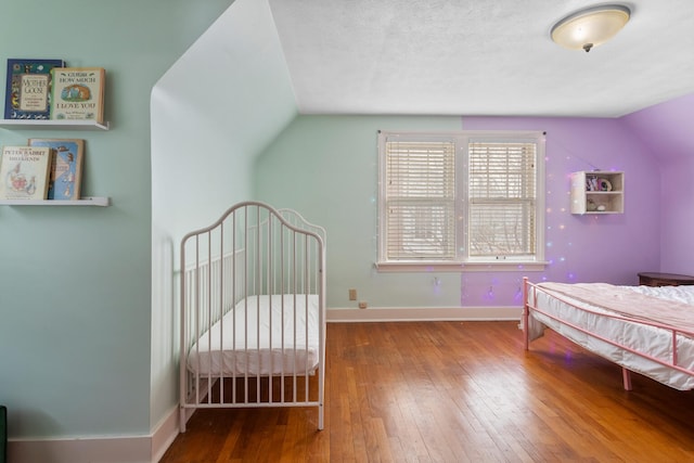 bedroom with hardwood / wood-style flooring, vaulted ceiling, and a textured ceiling