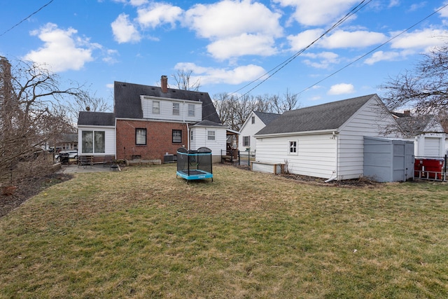 back of house with a yard and a trampoline