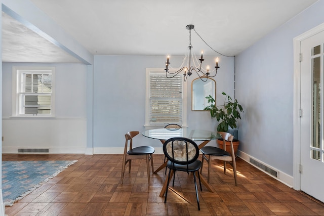 dining space with dark parquet flooring and an inviting chandelier