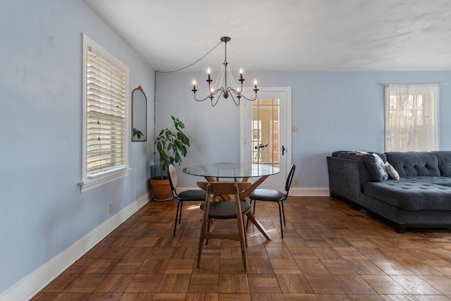 dining area featuring an inviting chandelier and dark parquet floors