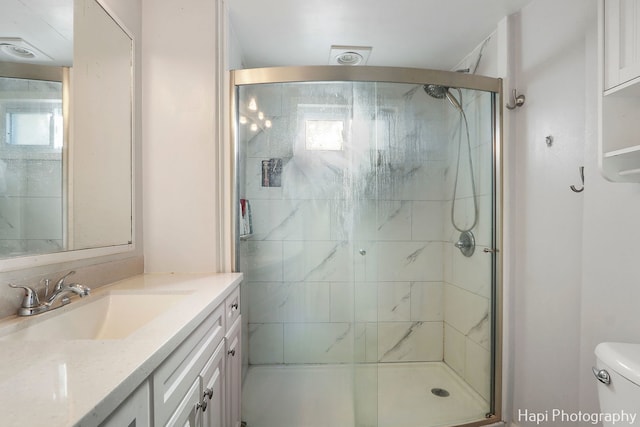 bathroom featuring vanity, a shower with shower door, and toilet