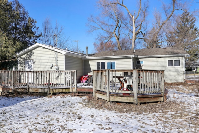 snow covered back of property with a wooden deck