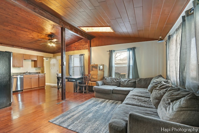 living room with sink, wood ceiling, ceiling fan, hardwood / wood-style floors, and vaulted ceiling with skylight