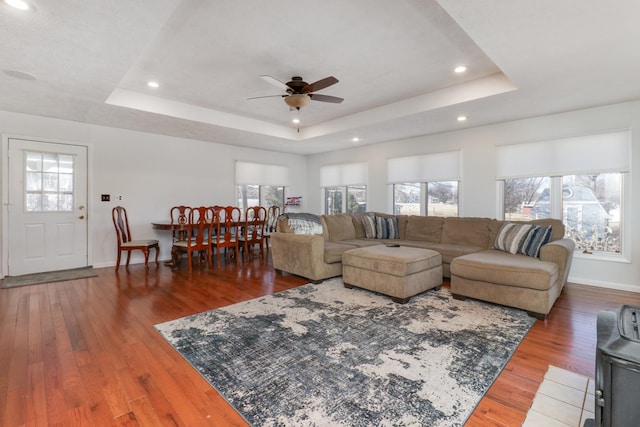 living room featuring a raised ceiling, hardwood / wood-style flooring, and ceiling fan